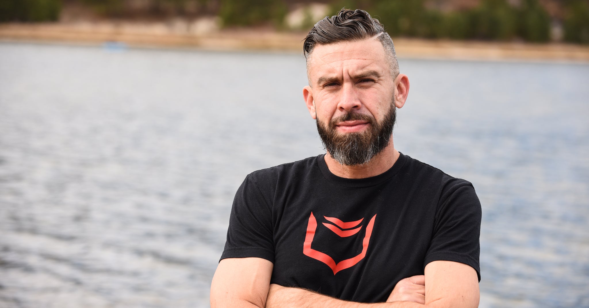 Photo of SHEATH founder, Robert Patton, standing in front of a lake with a SHEATH T-Shirt on