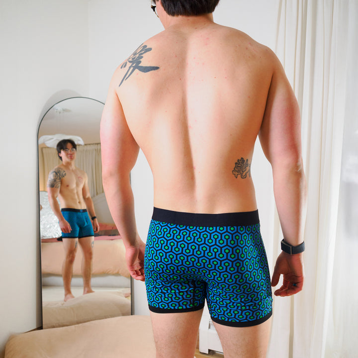 Man wearing SHEATH 4.0 boxer brief - Blue hexagon print standing in front of a mirror.