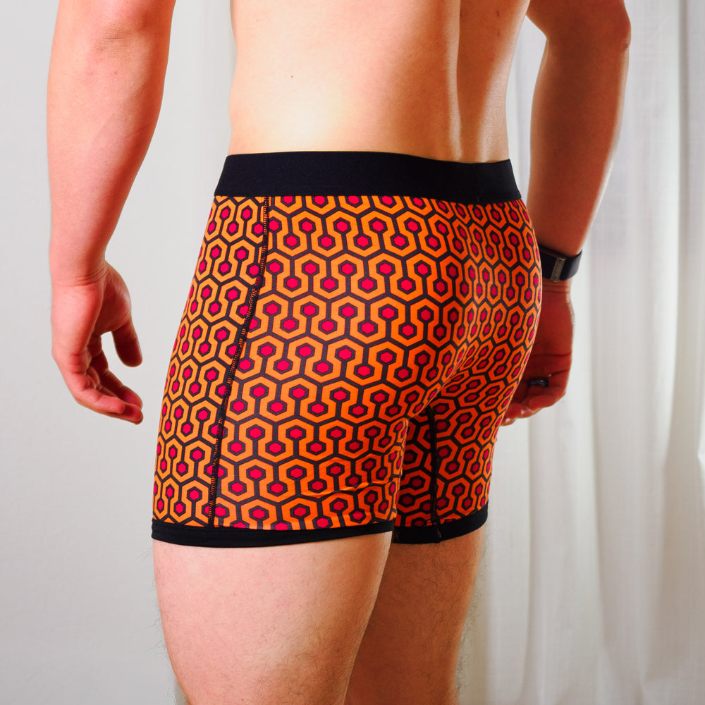 Person wearing SHEATH 4.0 boxer brief - Orange hexagon print against a plain background