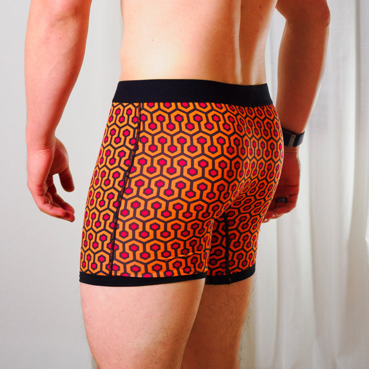 Person wearing SHEATH 4.0 boxer brief - Orange hexagon print against a plain background