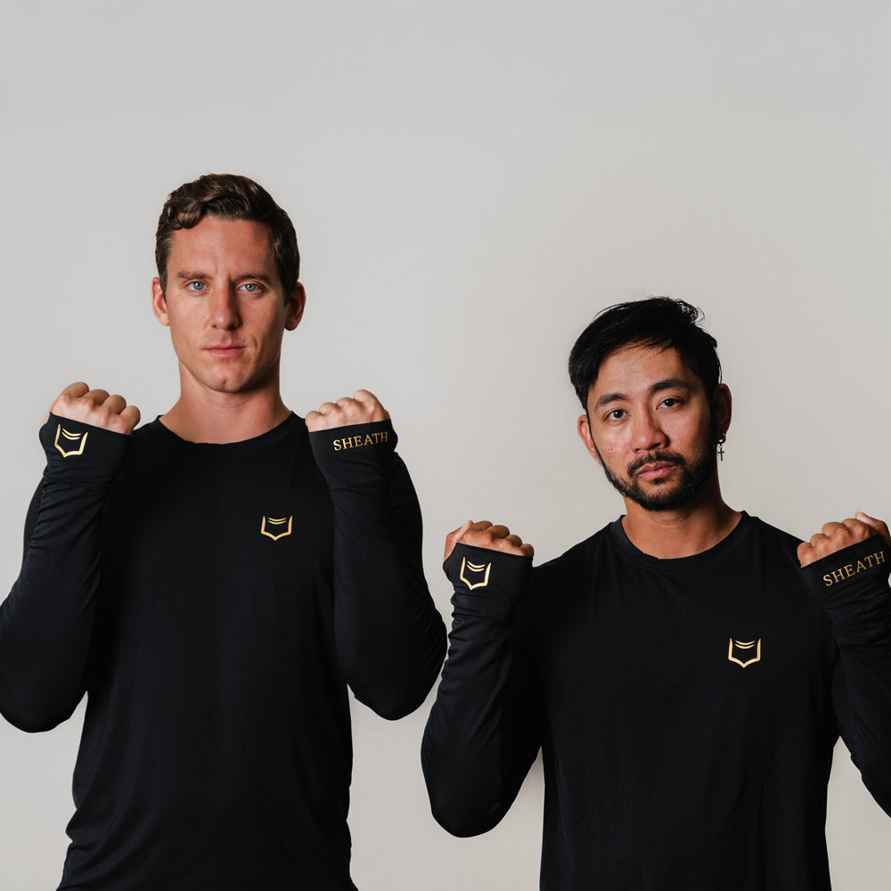 Two models wearing SHEATH Baselayer Top With Golden Heat Print Logo On Lapel and Cuffs - Black