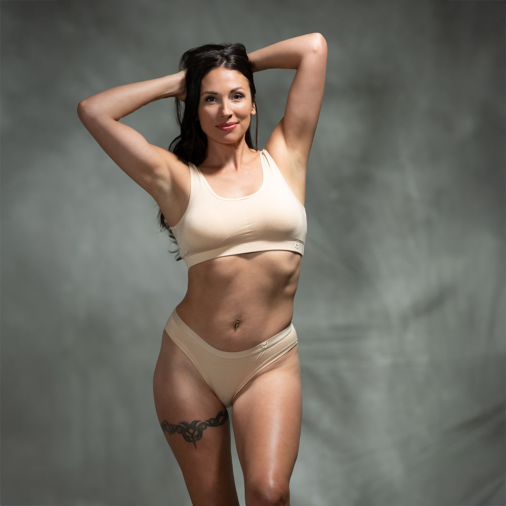 Female model wearing SHEATH Woman modeling nude-colored bikini briefs made from breathable bamboo fabric with support and anti-chafing features for all-day comfort. front view