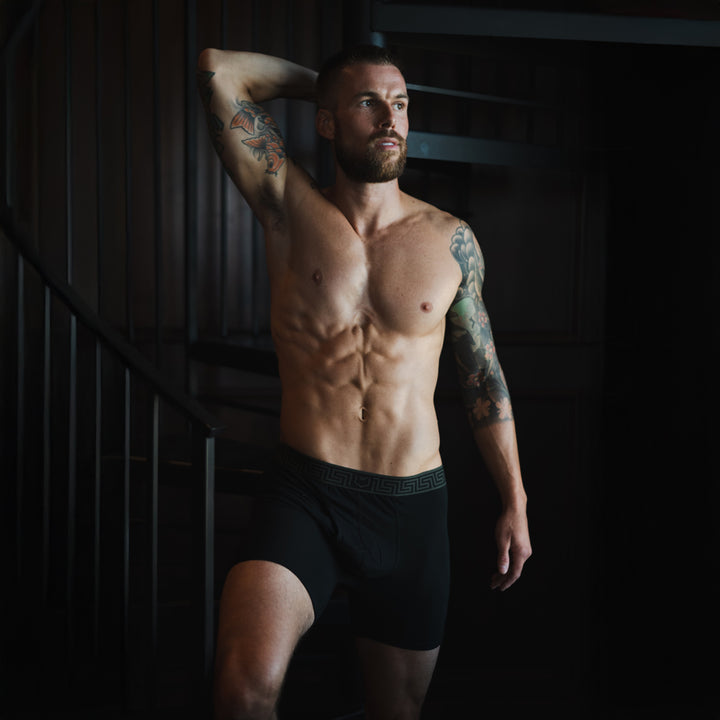 Posed male model wearing SHEATH black boxer briefs made from breathable bamboo airflow mesh fabric with ergonomic dual pouch support for anti-chafing comfort and everyday wear