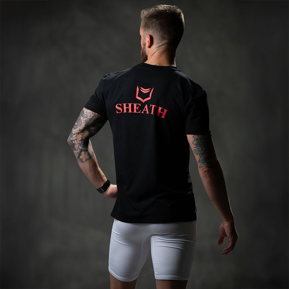 Male model wearing SHEATH black t-shirt featuring breathable bamboo fabric and a crew neck, with a large red logo between the shoulderblades for athletic and casual wear