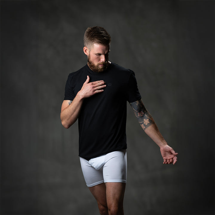 Male model wearing SHEATH black t-shirt featuring breathable bamboo fabric and a crew neck, with a black logo on the breast for athletic and casual wear