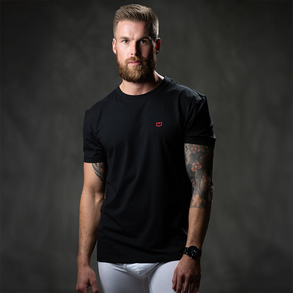 Male model wearing SHEATH black t-shirt featuring breathable bamboo fabric and a crew neck, with a red logo on the breast for athletic and casual wear