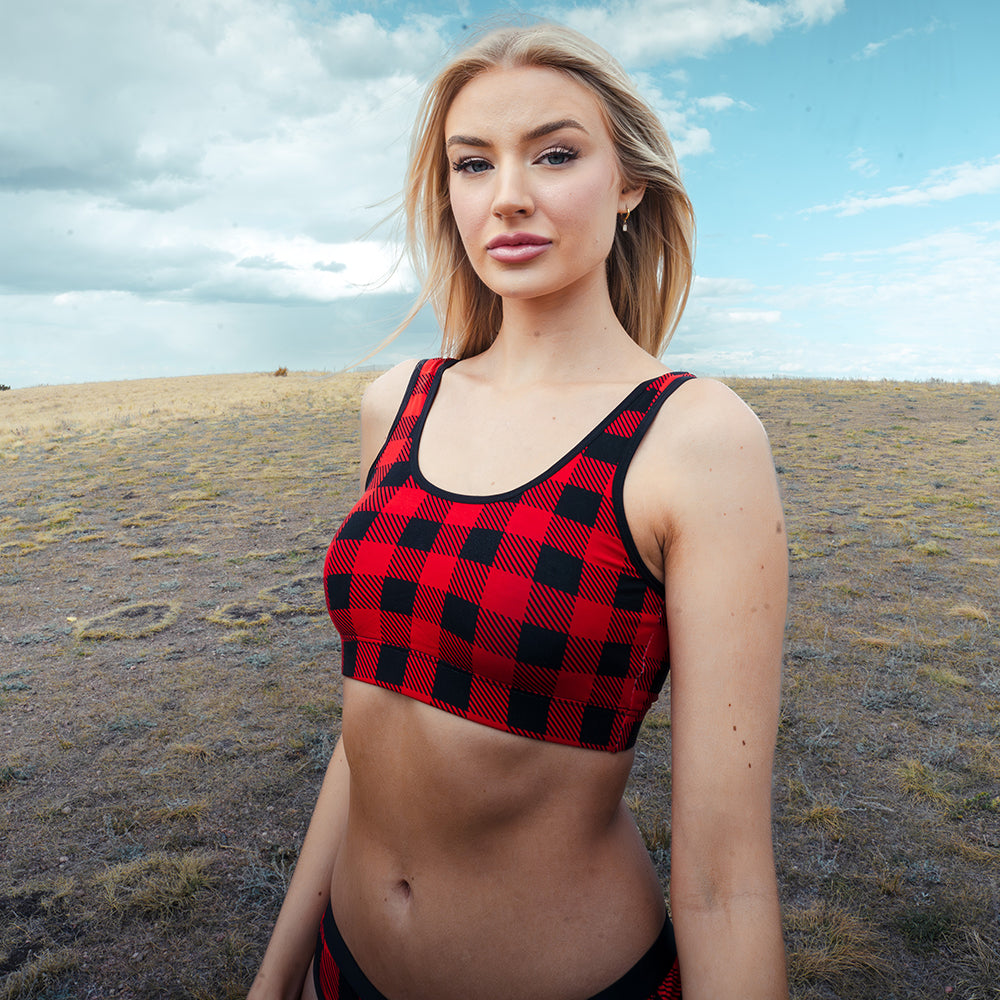 Woman wearing a red and black checkered bralette and matching bottoms in an open field